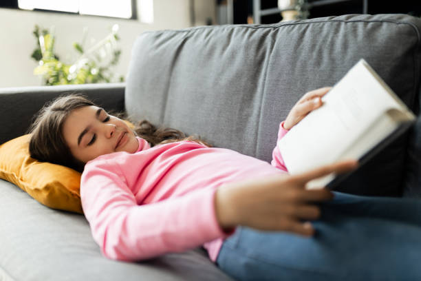 istock Girl enjoying her weekend and reading a book on the sofa 2150307085