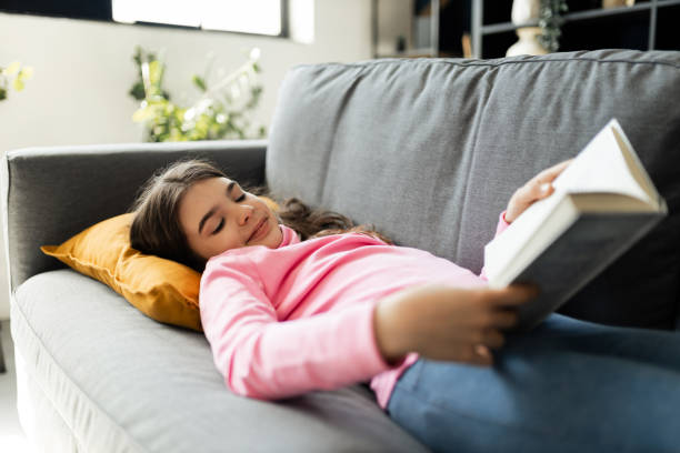 istock Teenage girl lying down and reading a book 2150307088