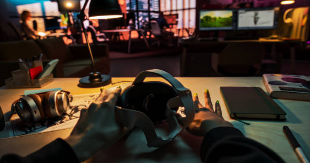 istock POV of a Person Picking Up a Virtual Reality Headset in Creative Office. Mock Up for Inserting Your Own VFX Virtual Reality 3D Universe, Digital Office Interface, Social Platform 2150307832