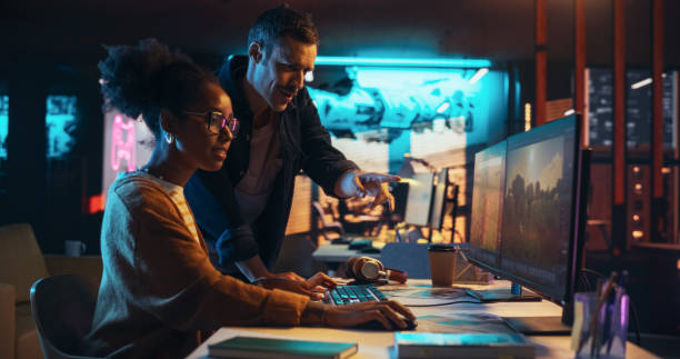 Two Stylish Diverse Employees Discussing Level Landscape on Computer in Game Development Company. Young Creative Director and Designer Talking About Work, Making Changes on Project