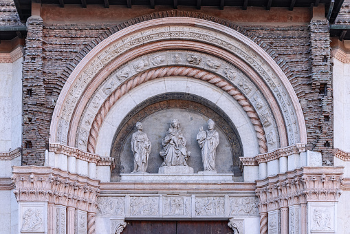The entrance arch of Bologna San Petronio Basilica features a sculptural triad set within a finely carved relief, highlighting the artistry of Italian stonework
