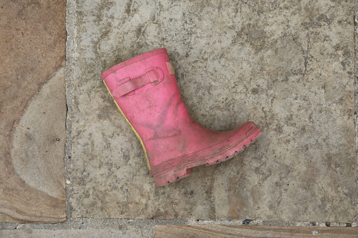 A single discarded rubber boot lying on a paving stone