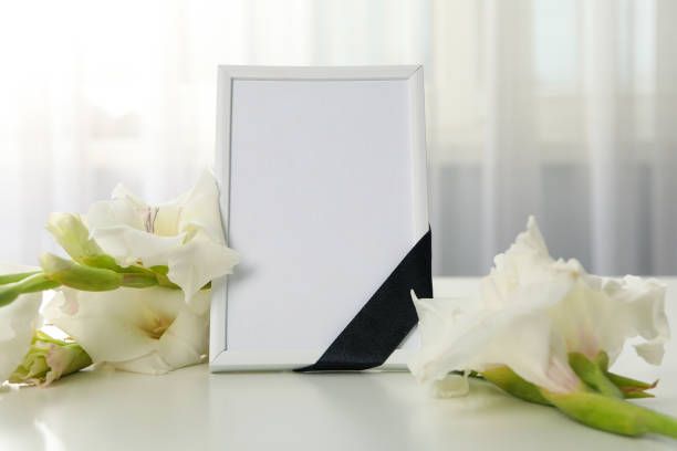 istock Photo frame with black ribbon and flowers on light background 2150310725