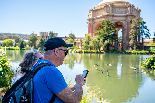 Mature woman and man photographing pond in San Francisco during springtime day