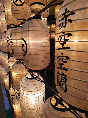 The brightly lit white lanterns with Chinese characters hanging against the backdrop of the night. The characters on the lanterns read 