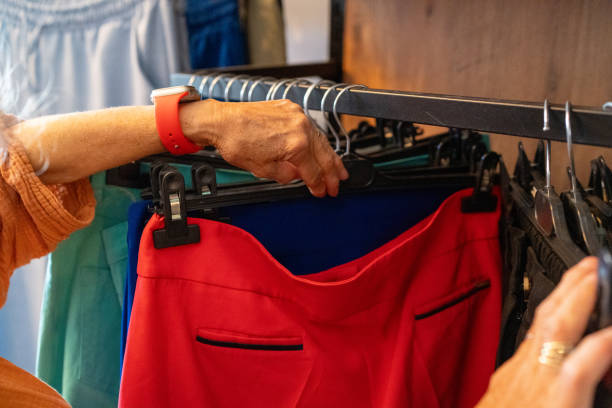 A woman browsing through clothes on hangers in a store, making selections