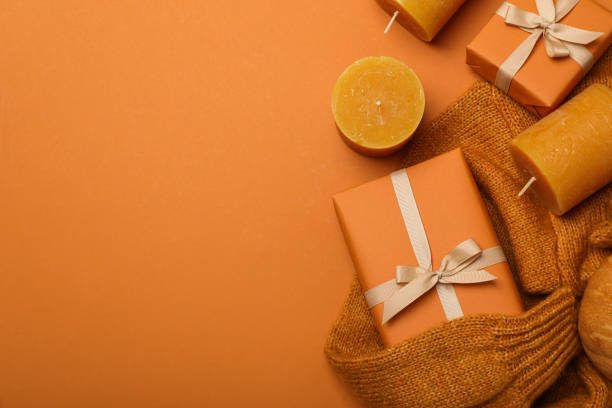 istock Candles and boxes on sweater on orange background, space for text 2150314980