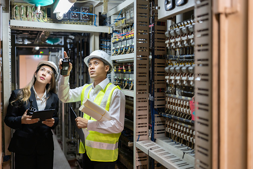 Within the ever-evolving energy industry, male and female engineers at the power plant work tirelessly to meet growing demands while minimizing environmental impact.