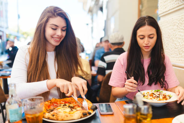 istock Two smiling young women eating at a restaurant 2150316353