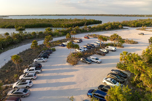 Parking lot at Florida Blind Pass beach on Manasota Key, USA. Vehicle parking area with cars parked on ocean beach parking lot. Summer vacation on beachfront.