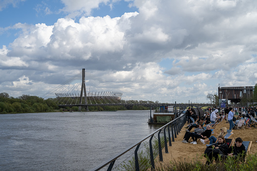 People relaxing on the artificial beach on the Vistula boulevard in Warsaw, with the national stadium visible far in the background.