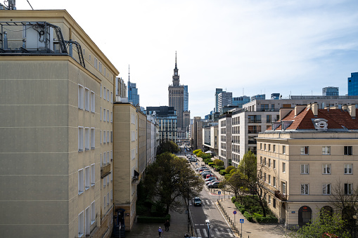 View of the Palace of Culture and Science in Warsaw, with a street and residential buildings below.