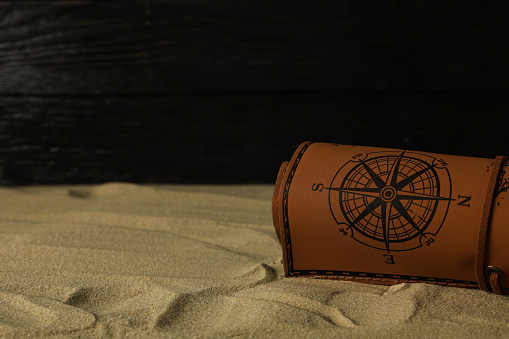 Columbus Day. A leather map lies on the sand