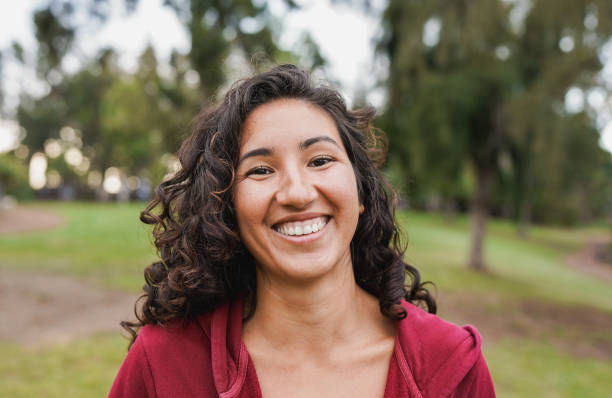 portrait of native american woman smiling on camera with city park in background - indigenous girl outdoor - latijns-amerikaanse-etniciteiten-fotos stockfoto's en -beelden