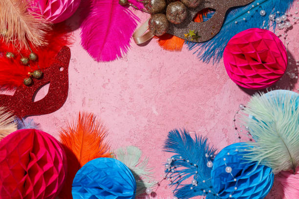 Carnival masks and feathers on pink background, space for text