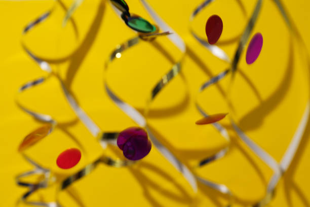 Serpentine and confetti on yellow background, close up