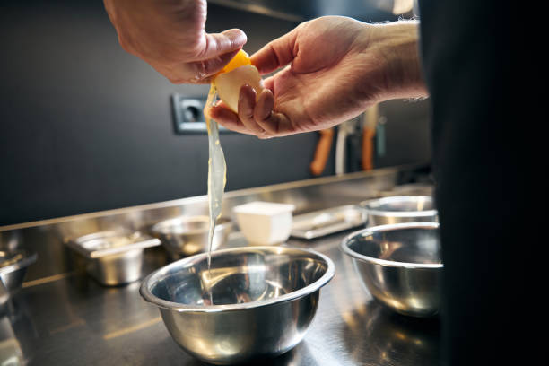 istock Cropped man breaking egg in bowl in modern restaurant 2150321441