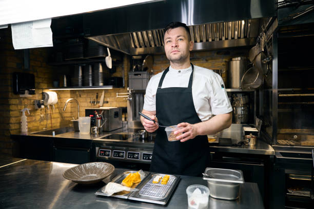 istock Caucasian chef holding box with nuts before putting them with spatula on cookie 2150321539
