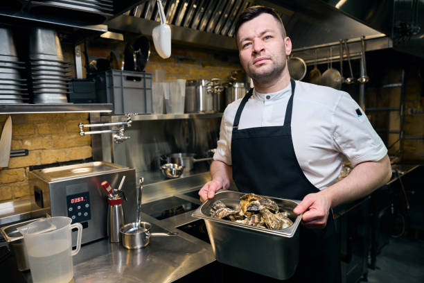 istock Caucasian chef holding bowl with oysters on kitchen in restaurant 2150323721