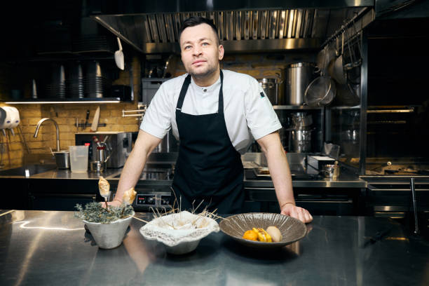 Caucasian male chef standing at table with three dishes in restaurant