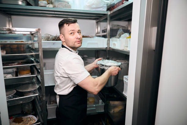 istock Caucasian male chef putting dish in saucepan on shelf in refrigerator storage 2150323744