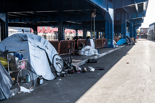 There is a huge social issues with Homeless camps  in poor neighborhood of San Francisco. Here a homeless camp under highway with tents, personal belongings, bike, trash during springtime day.