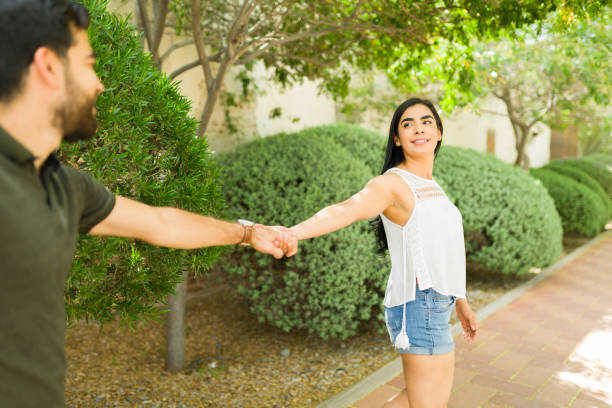 istock Pretty young latin couple playfully holding hands and smiling while strolling through a beautiful outdoor garden setting 2150325176
