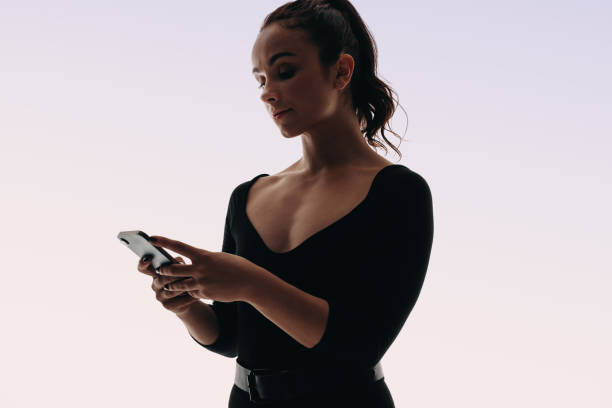 istock Fit young woman holding a smartphone, standing in a studio. 2150325965