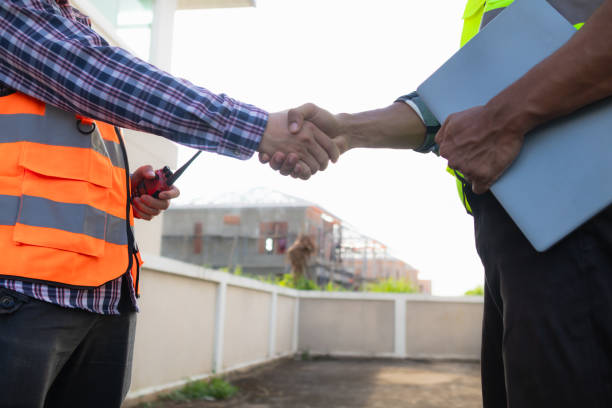 istock Behind the scenes foreman wearing reflective vest and hard hat inspects construction site to ensure construction meets engineering team's design plans and for the beauty and safety of residents. 2150327300