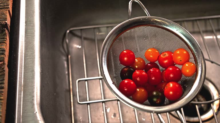 Pouring water with little tomatoes after washing into sink