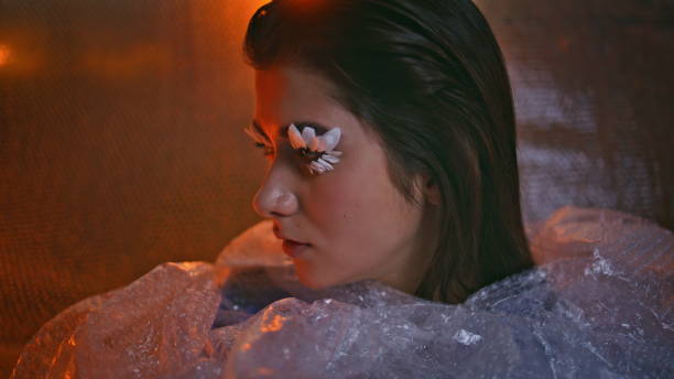istock Imaginative makeup woman posing in bubble pack with petal eyelashes closeup. 2150330427
