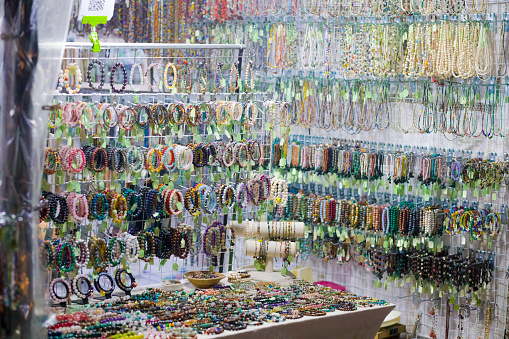 View into open jewelry item market stall and shop on night market ตลาดกรีนวินเทจ รัชโยธิน / Green Vintage Market Ratchayothin in Bangkok Chatuchak at Phahonyothin Rd. Shop is offering many bracelets and necklaces