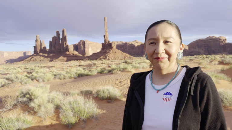 Navajo Woman in Her Forties in Front of Totem Pole Rock in Monument Valley Tribal Park Utah Holding an I Voted Sticker Signifying that She Just Voted in an American Election