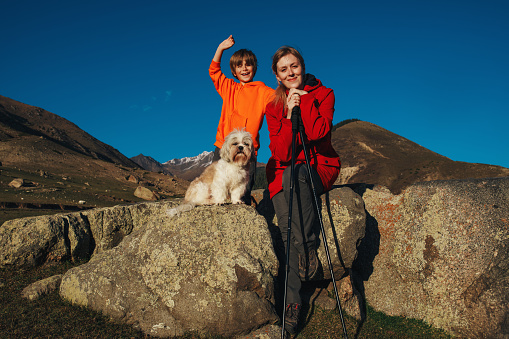 Happy mother and son with shih tzu dog portrait in the mountains