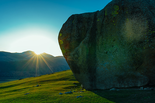 Picturesque mountain view with huge boulder at sunset