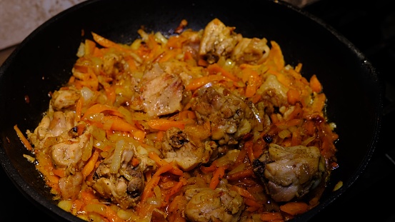 Homemade Korean Spicy chiken dish, frying chiken with carrot in a pan with sunflower oil