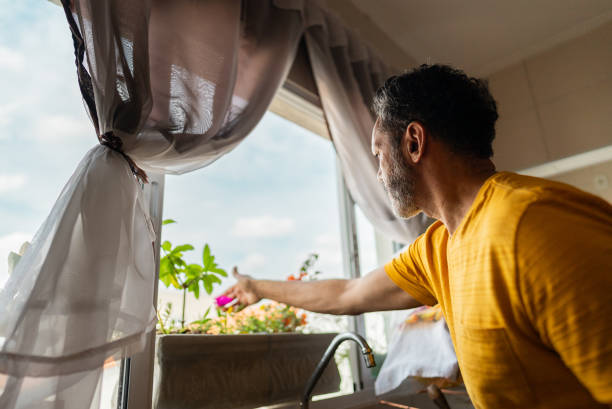 handsome young man looking through the window to the street on a summer day