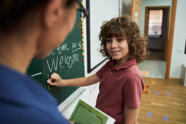 istock Jolly kid writing on blackboard during lesson 2150338286