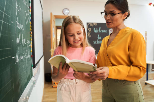 Happy female tutor with pupil in class room
