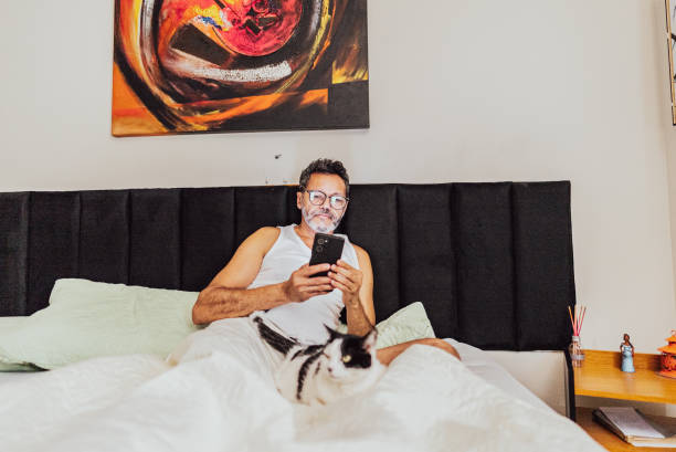 istock Mature man using mobile phone on bed in the bedroom at home 2150338403