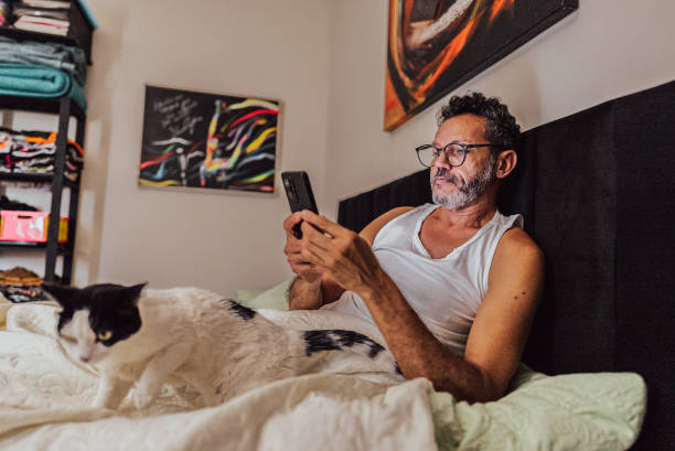 istock Mature man using mobile phone on bed in the bedroom at home 2150338406