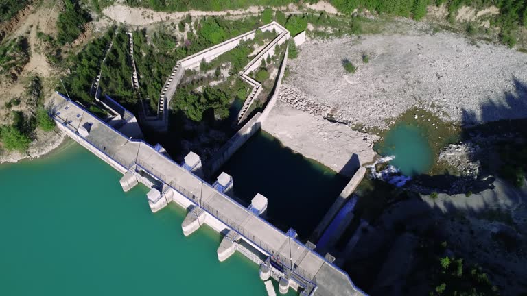 Water reservoir captured in mountain valley, drone view. Water reservoir, emerald lake in wooded scenery. Water reservoir and dam aerial footage, secluded area