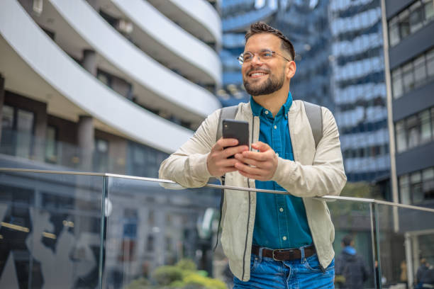 istock Young smiling man using smartphone on the street 2150339589