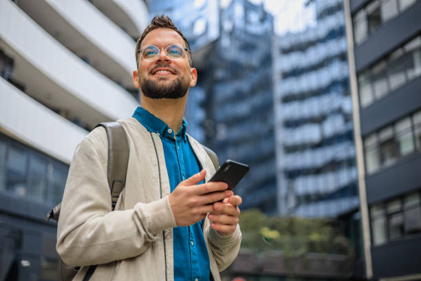 istock Young smiling man using smartphone on the street 2150339591