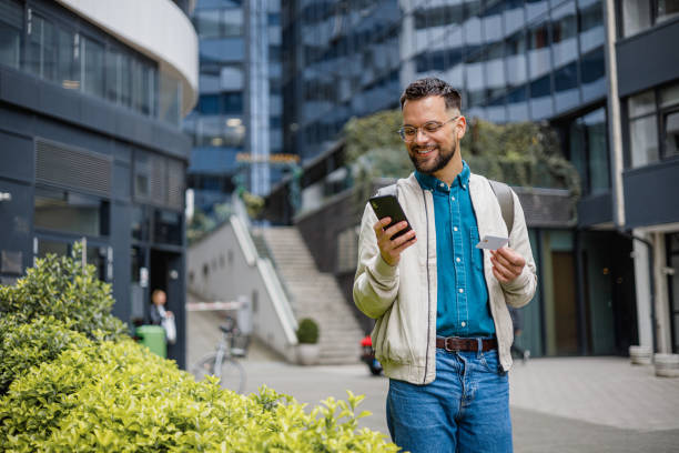 istock Cheerful young man using phone and credit card on the go 2150339759