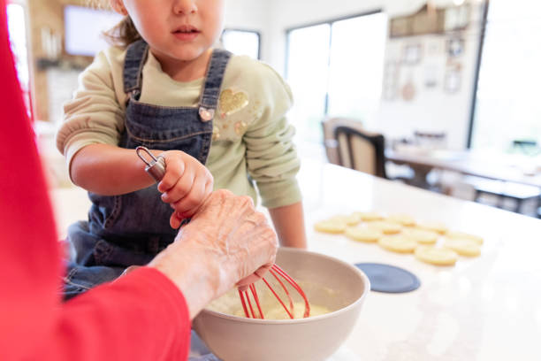 The unrecognizable young girl helps her grandma make cookies in the kitchen.