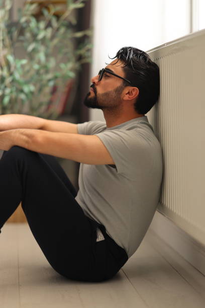 istock Man sitting alone at home looking sad and distraught 2150344316