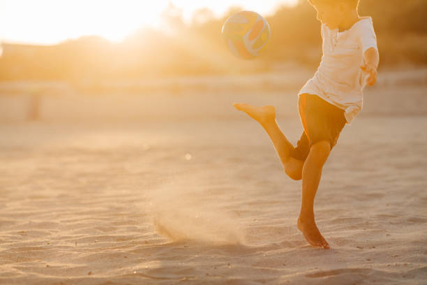 Phuket, Thailand - November 10,2024: People play soccer as the sun sets on the Commemoration of Princess Mothers Stadium field at Karon Beach, a popular tourist destination on the west coast of Phuket, Thailand.