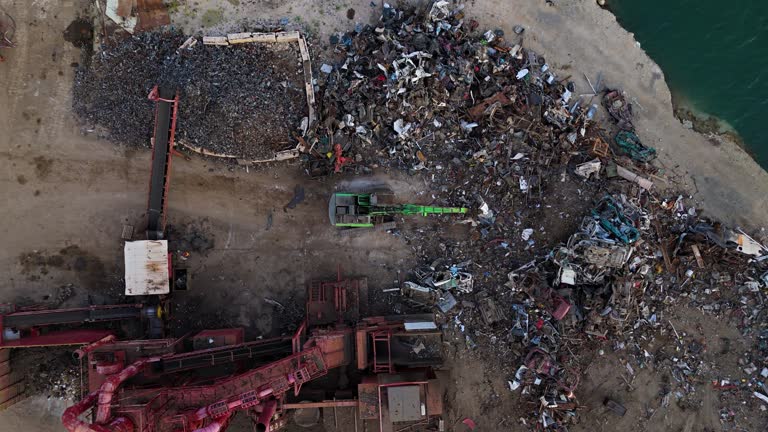 Drone top down descend on metal scrapyard or recycling center with crane at center working