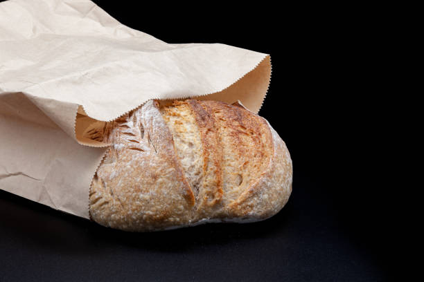 istock Black rye bread in flour and kraft paper bag on black background 2150352586